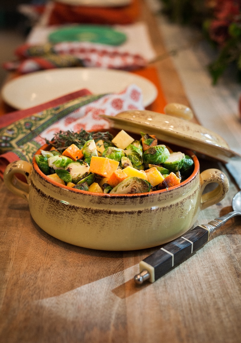 A photo of a dining table with a full casserole dish containing vegetables and squash.