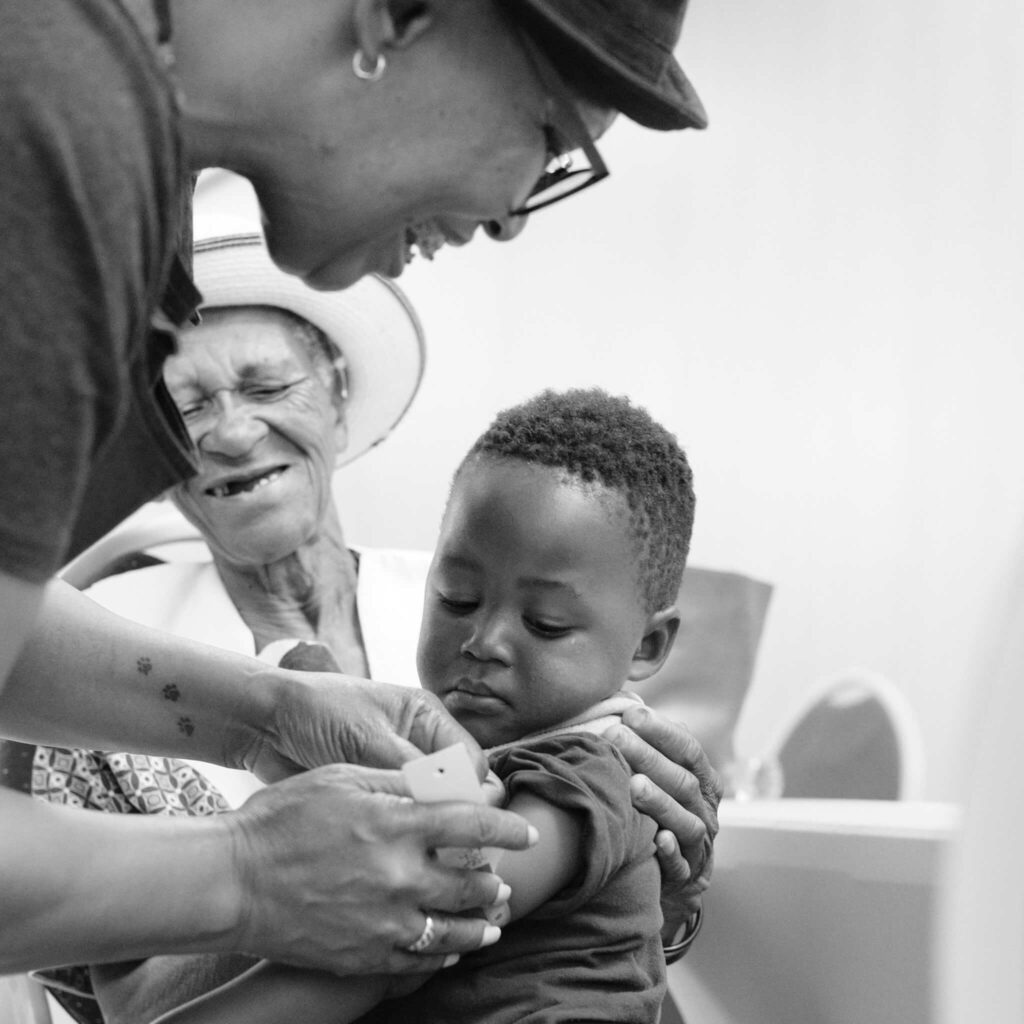 A photo of a woman measuring the mid-upper arm circumference of a young boy.